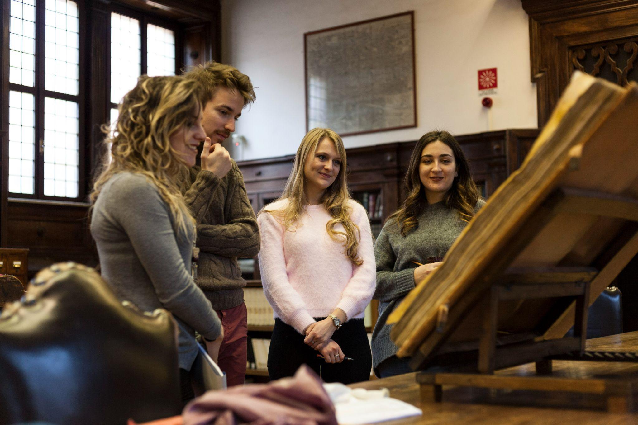 students completing an MA in Art History looking at an ancient book