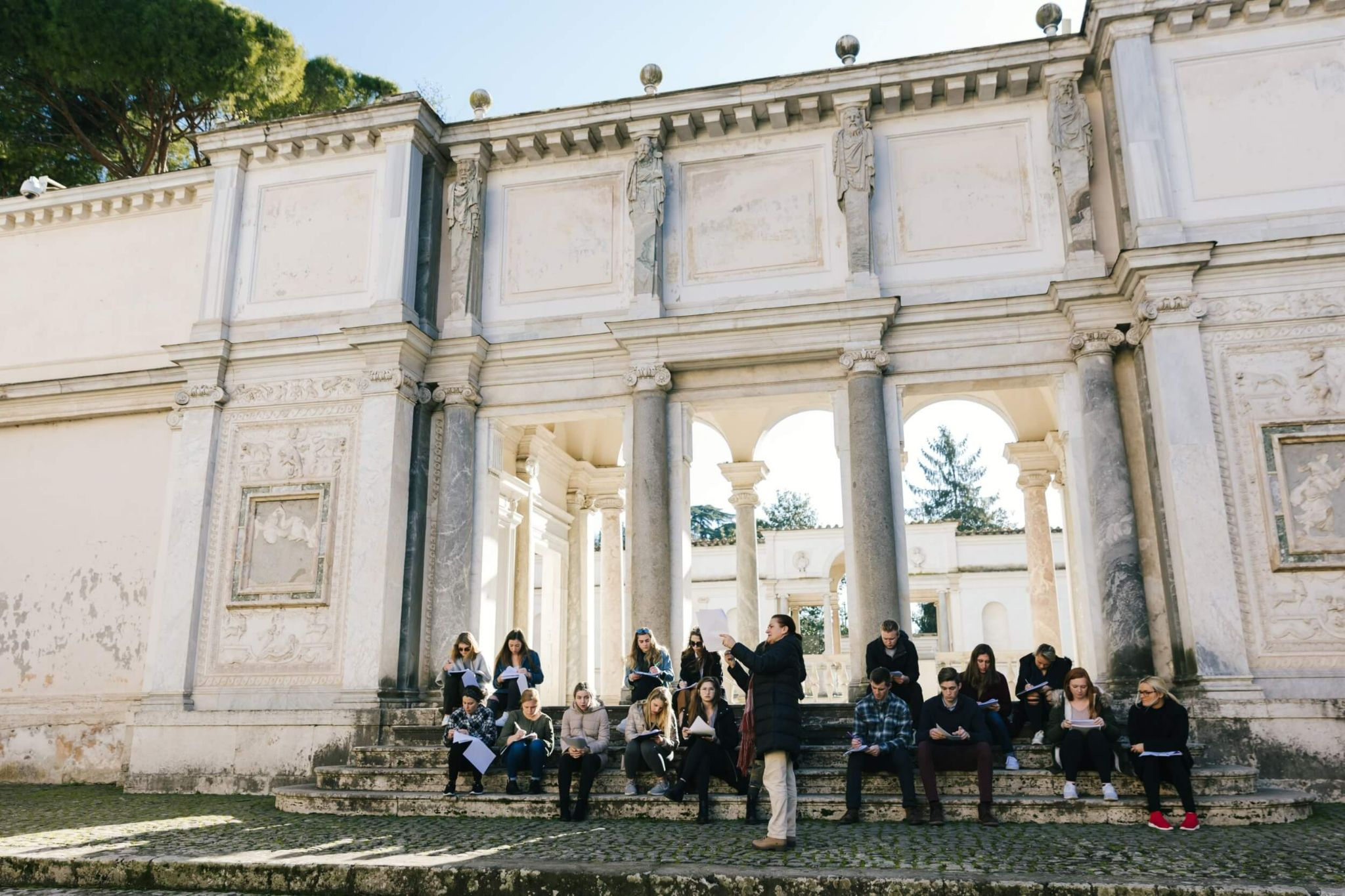Students who study art history in Rome learning about an ancient monument on site