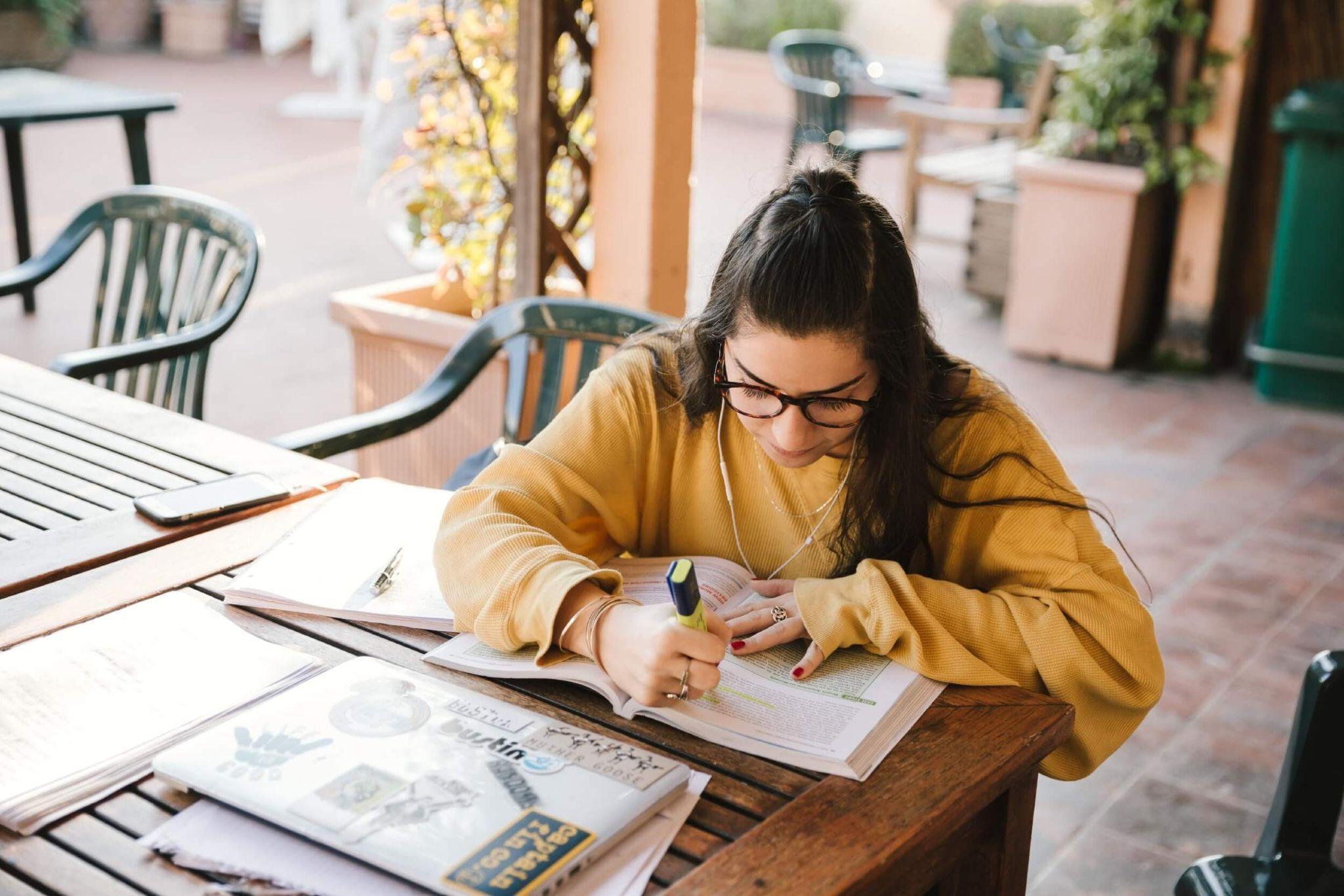 JCU student highlighting textbooks and studying while sitting outside.