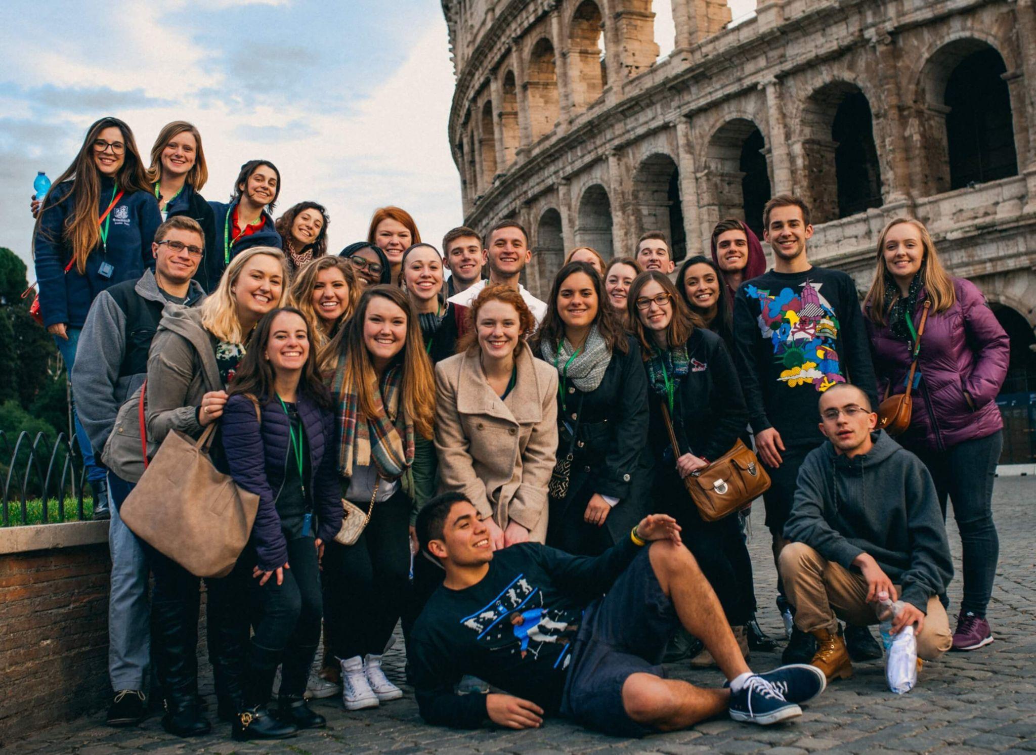 Group of John Cabot University students in front of the Colosseum, sharing a moment of joy during their sustainability studies.