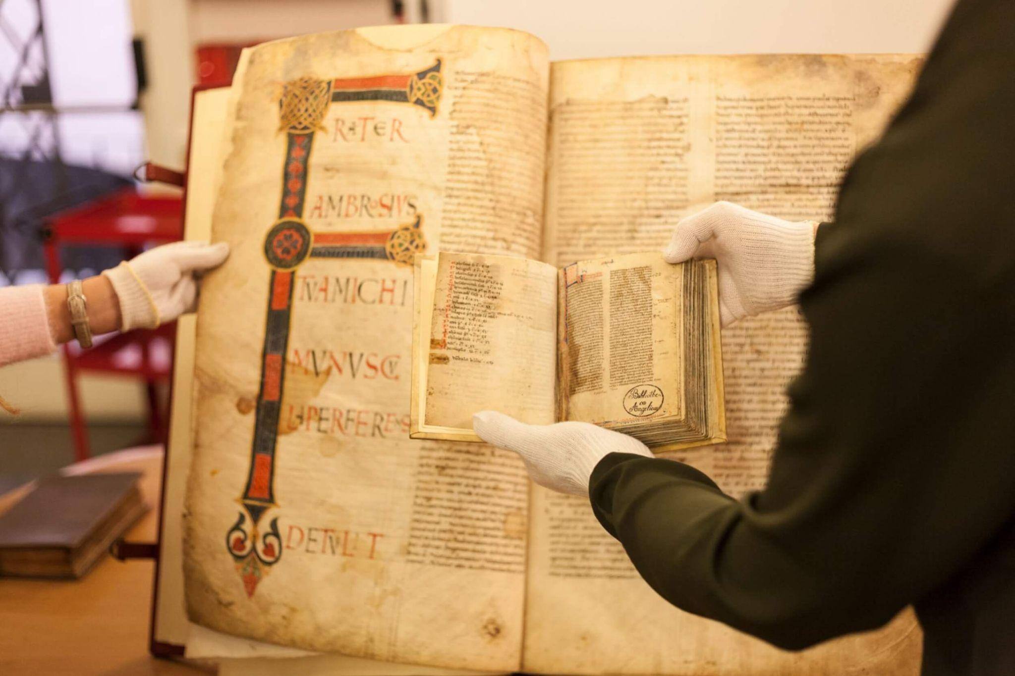 A class of students viewing an ancient book as they study art history in Rome