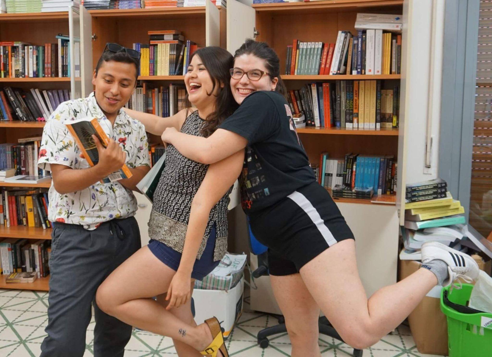 3 laughing JCU students posing in a library