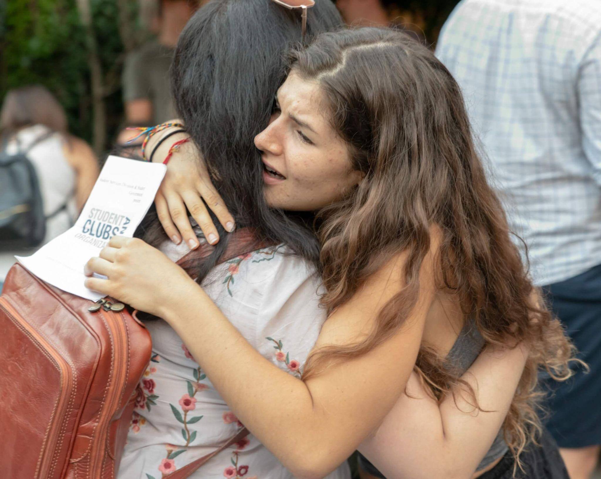 Female student hugging another while pursuing sustainability education at JCU at a student's club meeting