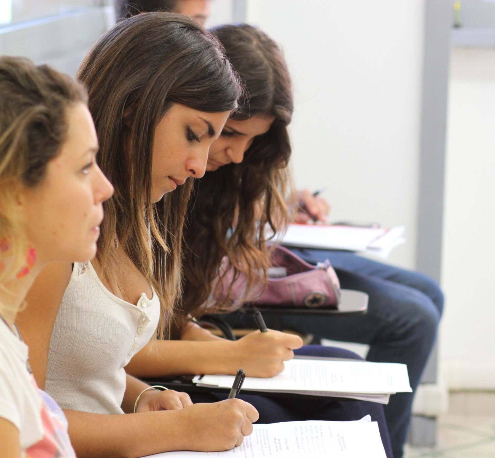 A row of John Cabot students completing coursework in a lecture