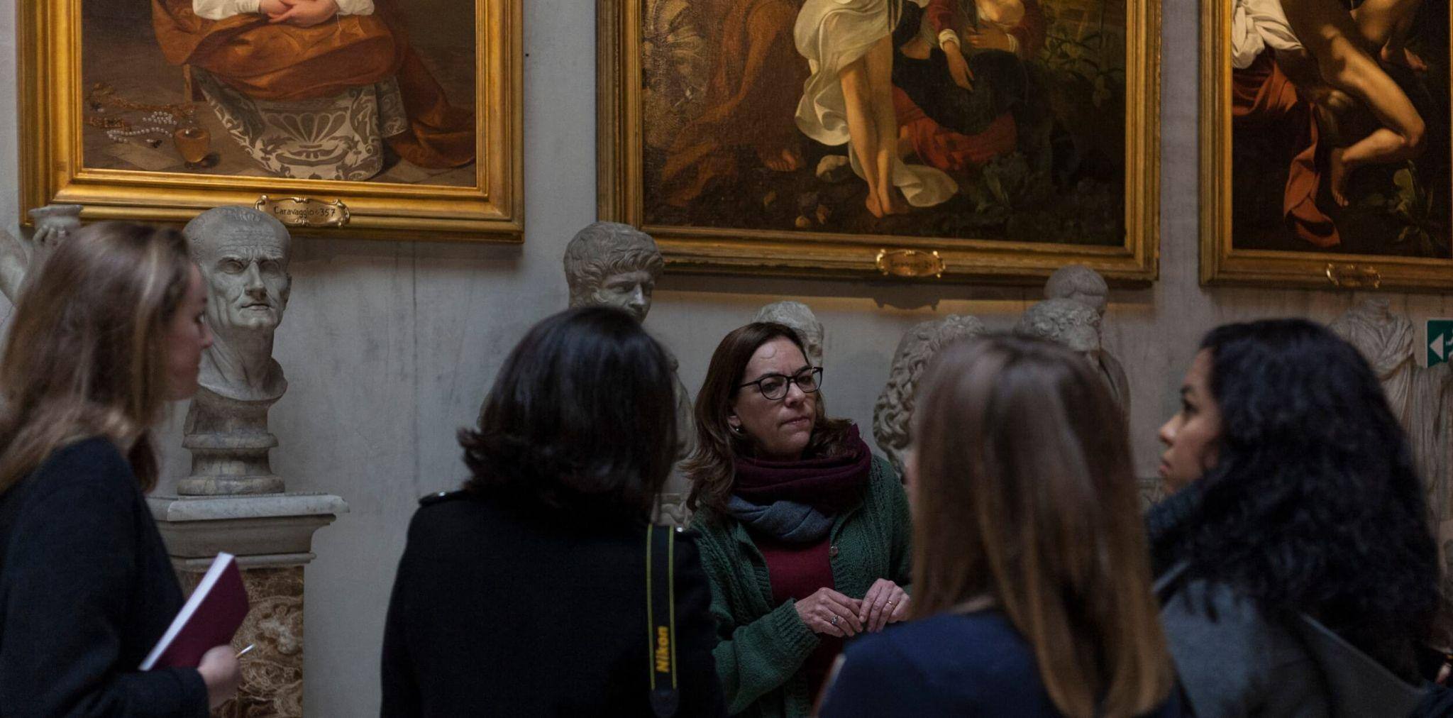 A group of art major study abroad students exploring a historical monument with a lecturer