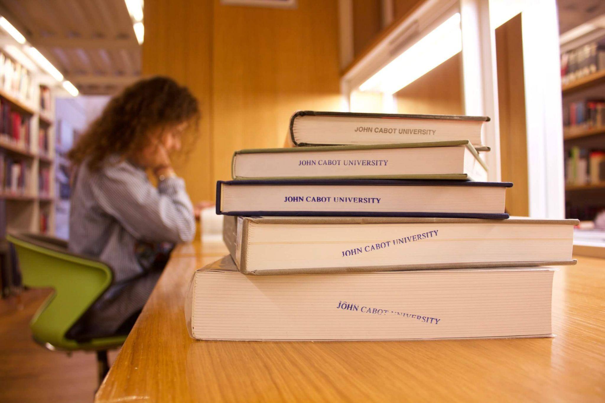 A focused female student studying her notes in a library at John Cabot University