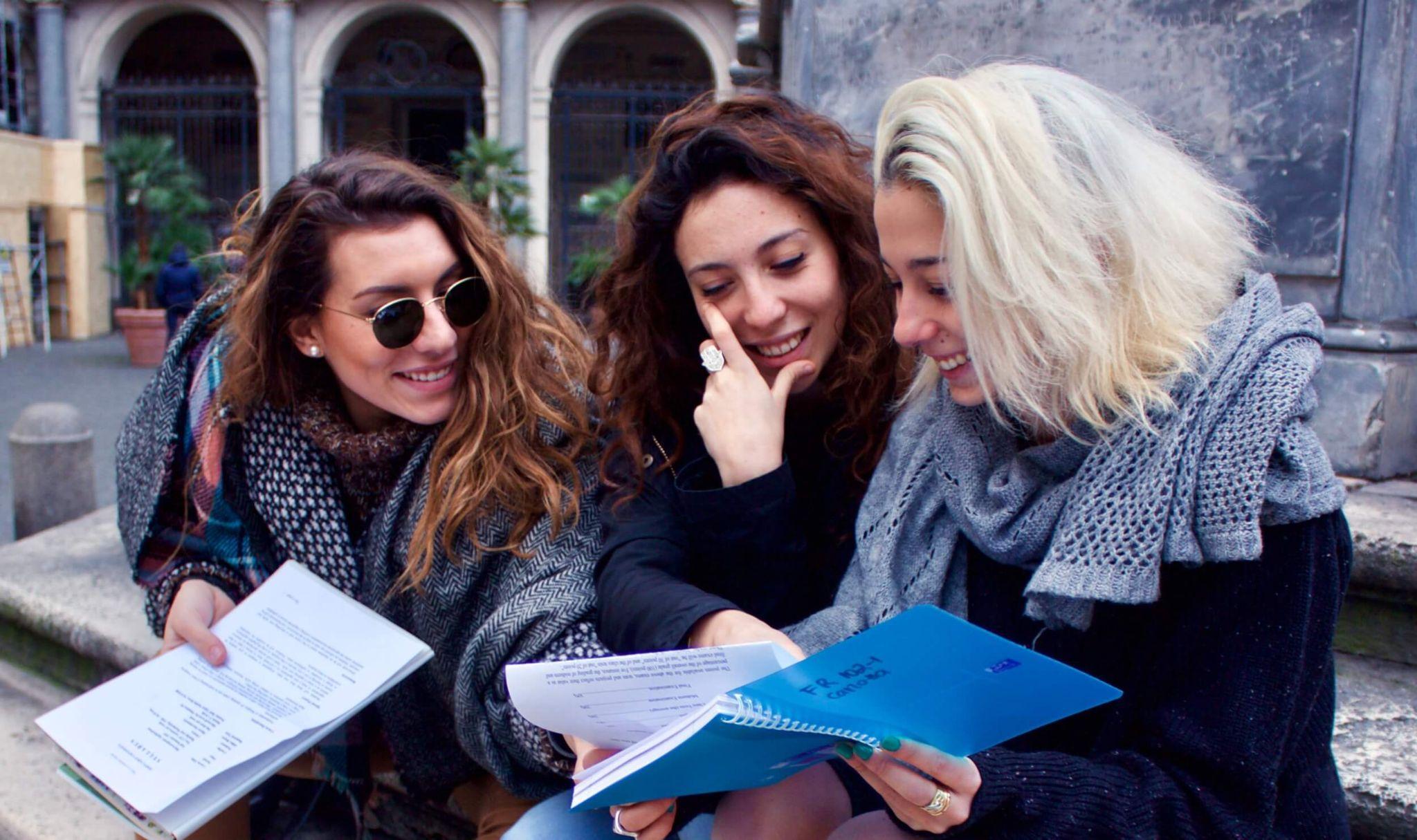 Three John Cabot University students engaged in a collaborative study session outdoors, focusing on their Certificate in Sustainability coursework