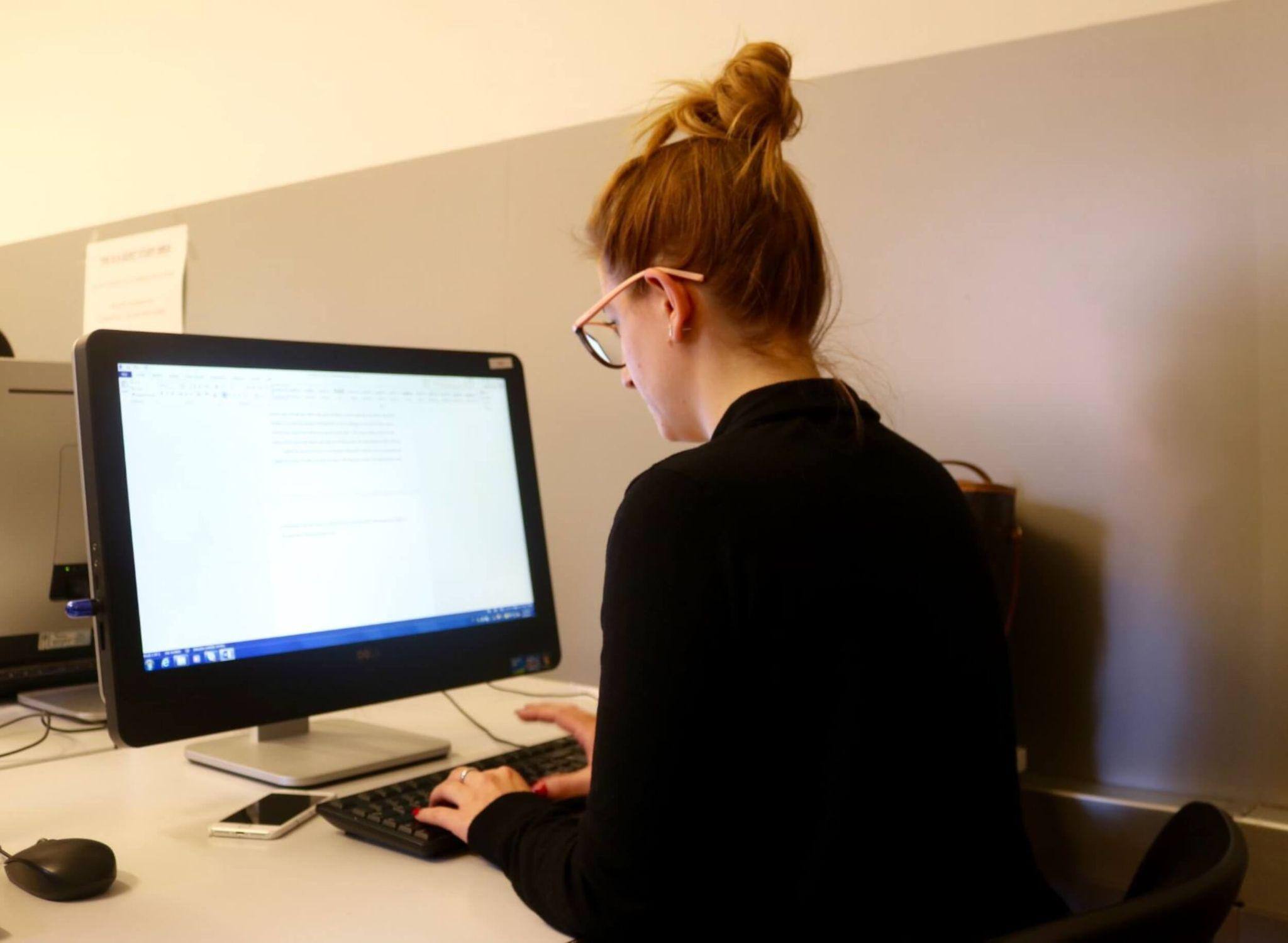 An art history degree seeker completing work at a computer desk