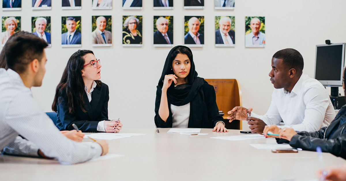 four people sitting at a round table having a conversation