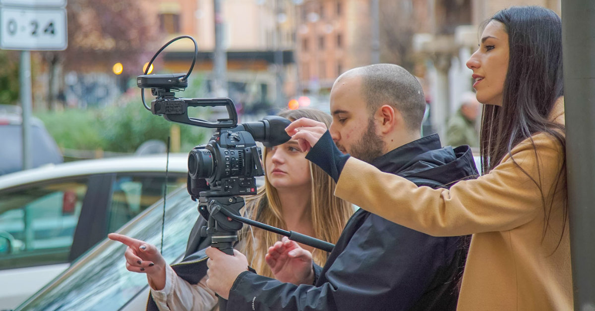 Three students operating a filming camera all facing the left hand side of the image