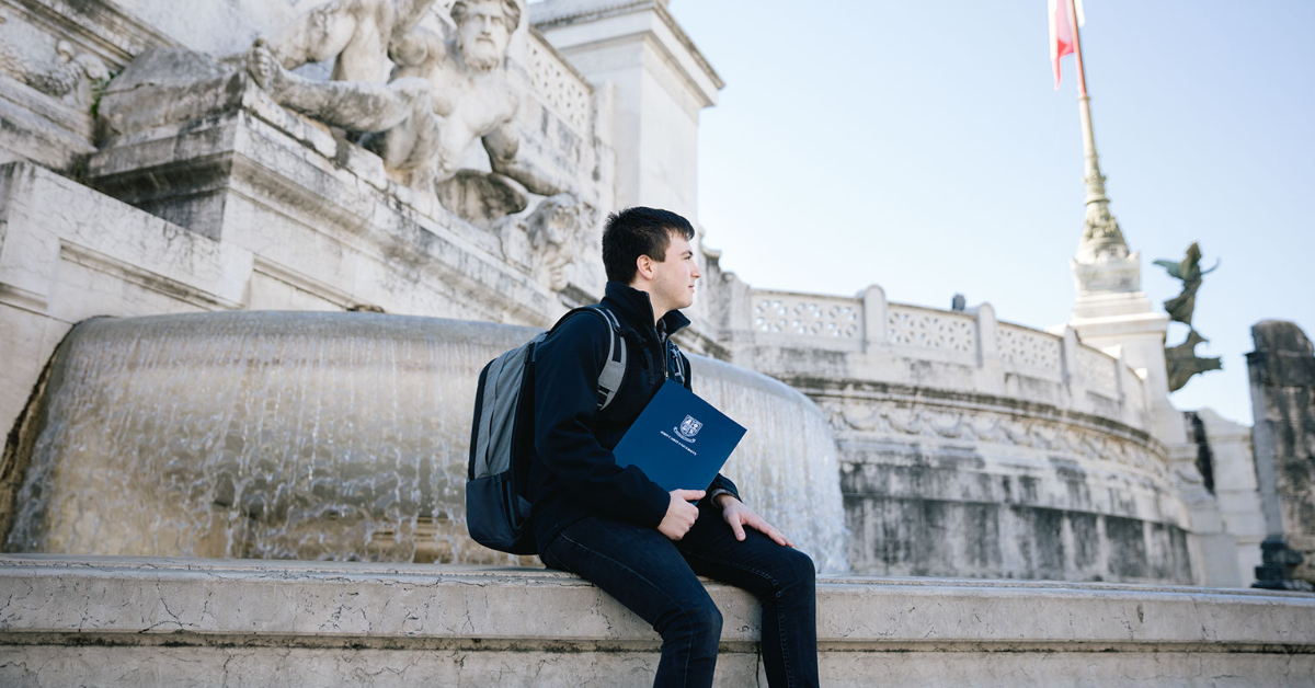 Boy sits in front of a fountain at Piazza Venezia