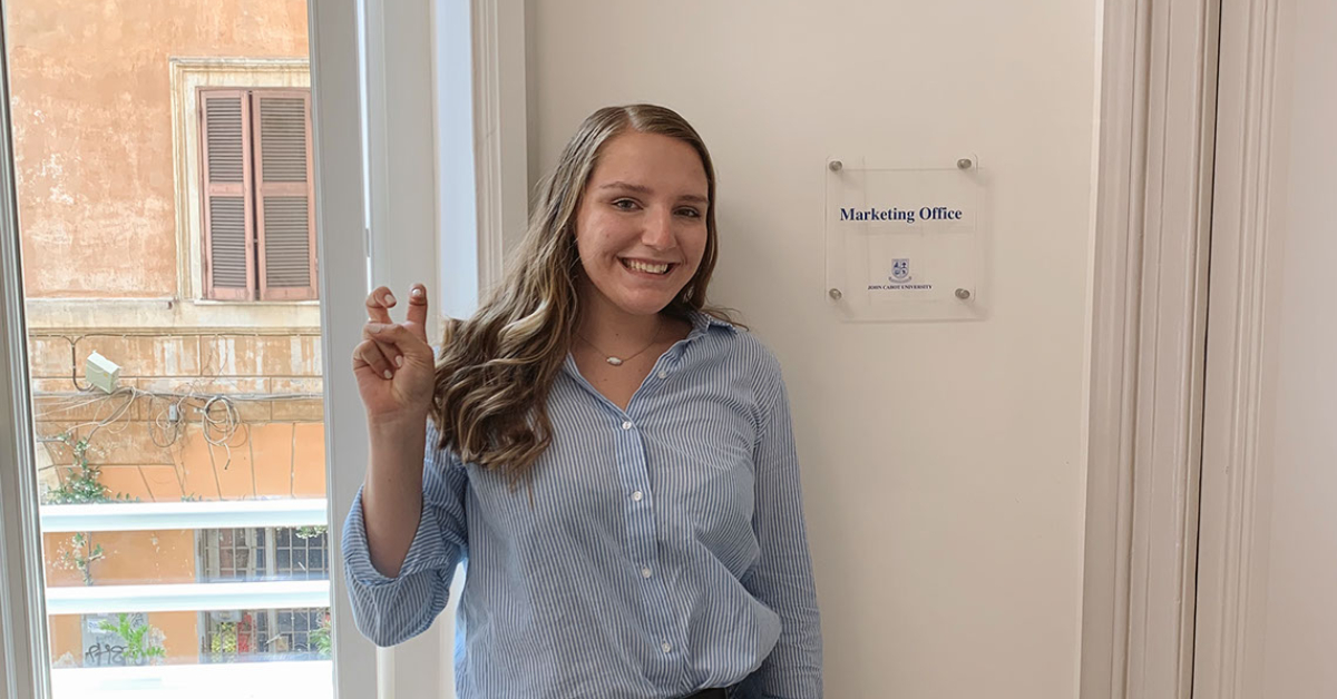 Study Abroad student holding up her home school's symbol