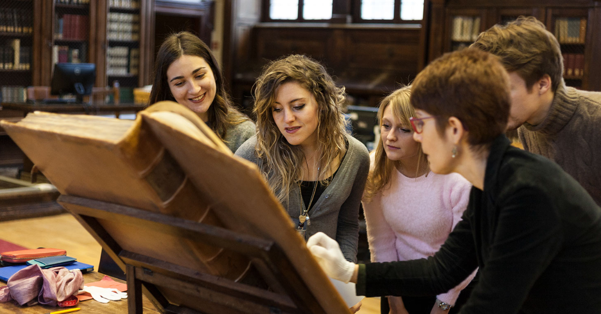 Professor and students observing an ancient book