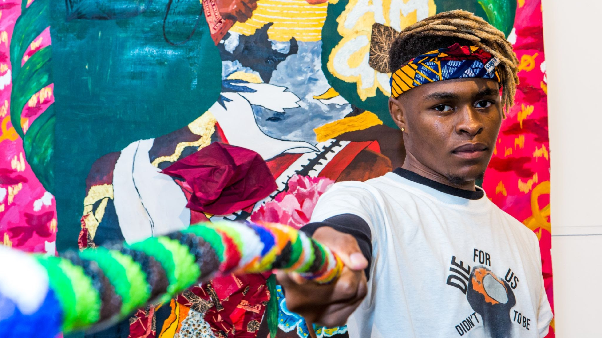 Student and artist Giggs Kgole standing in front of one of his art works