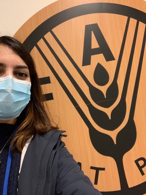 Ragazza con mascherina si trova davanti al logo della FAO 