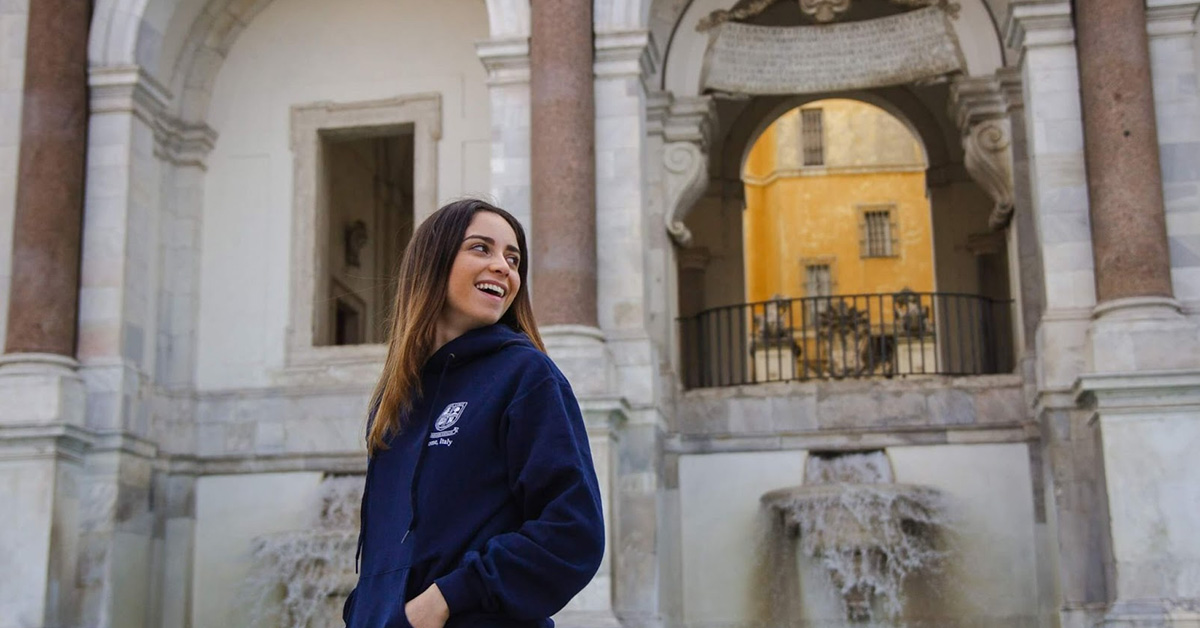 John Cabot University student smiling in front of a building