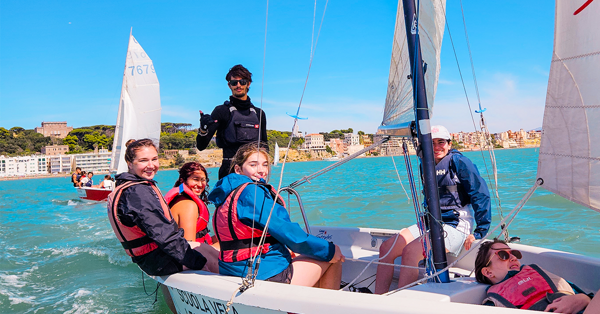 A group of students from JCU’s university in Rome sailing on the sea in a small boat, smiling and enjoying the experience.