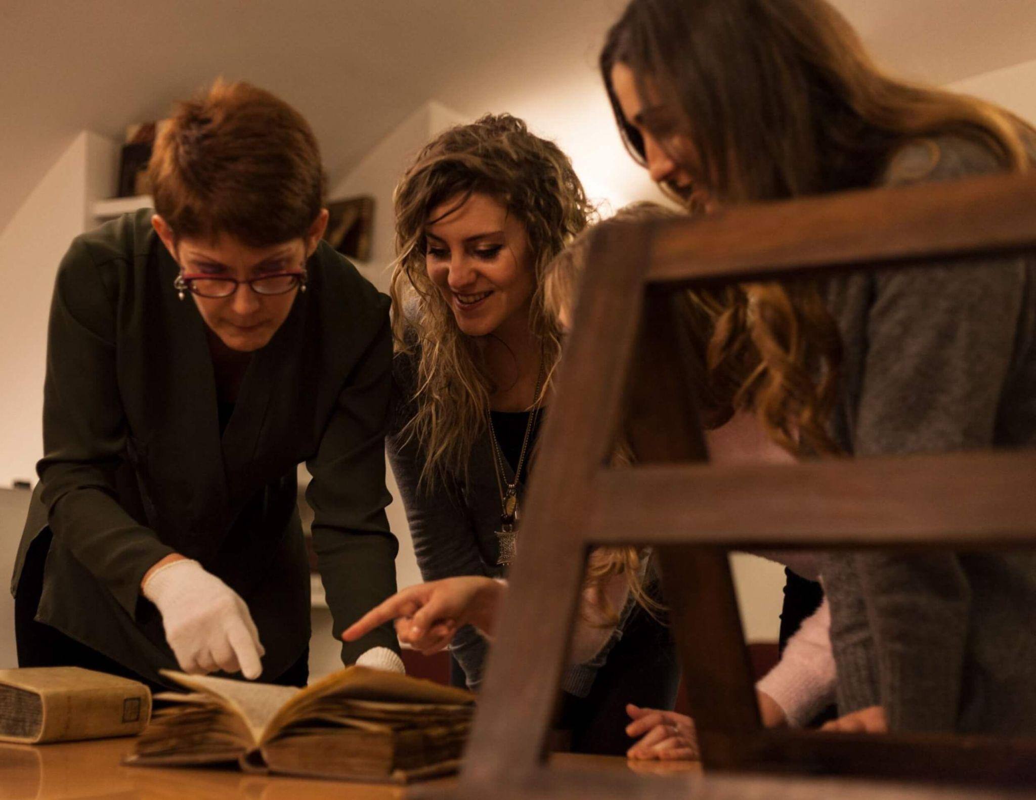 A pair of students examining an artifact with a professor as they study art history in Rome